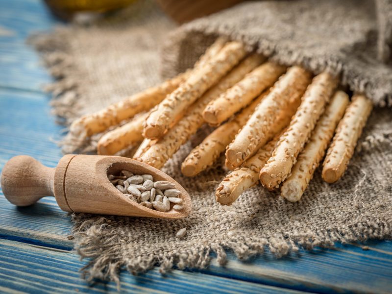 Fresh baked grissini bread on wooden board. Selective focus.