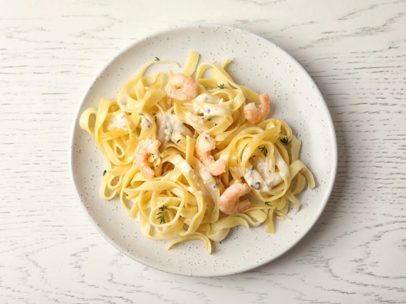 Delicious pasta with shrimps on white wooden table, top view